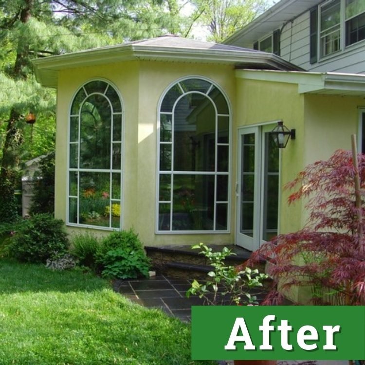 a yellow custom built addition with tall windows that reflect the greenery in the nearby garden