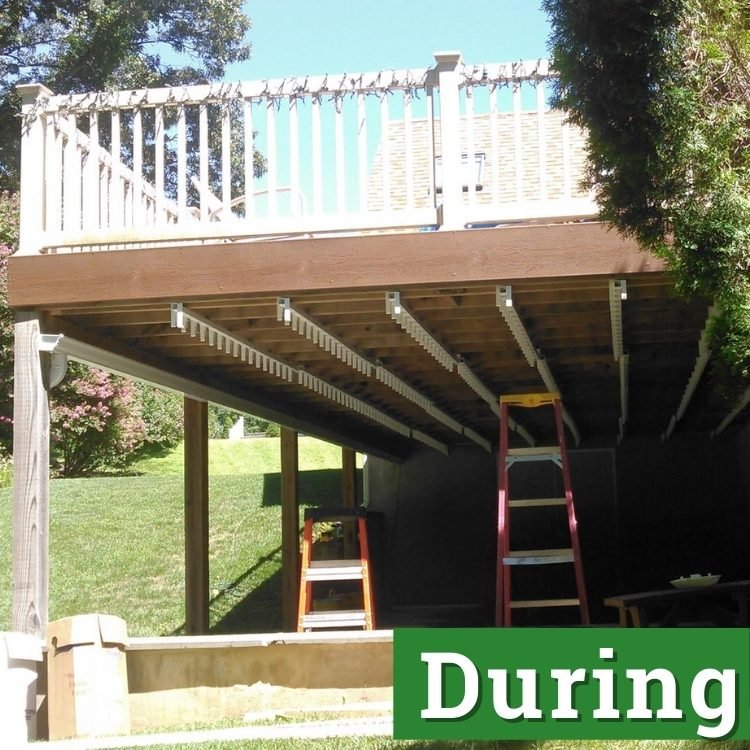 two ladders stand under a second story deck in the process of being built