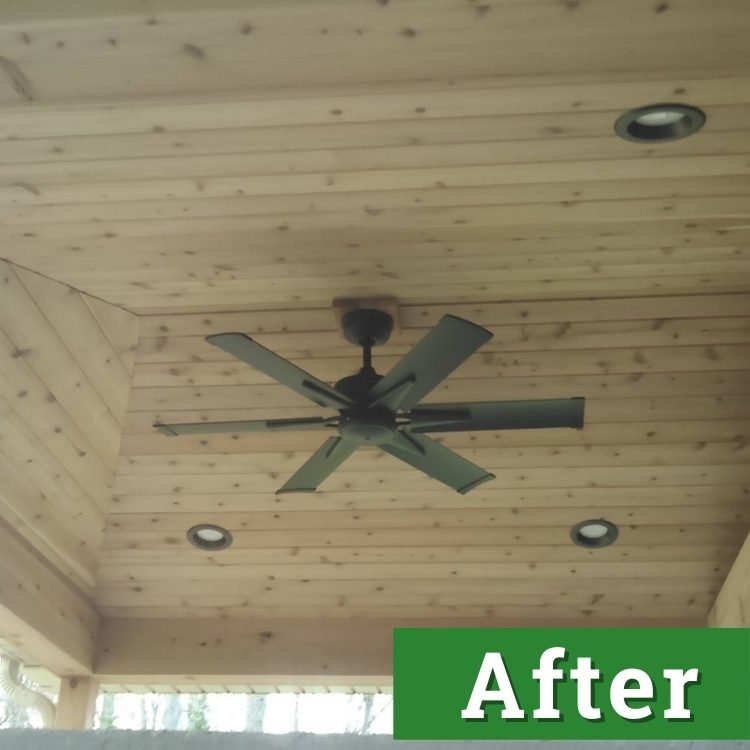 a black fan installed in a wood paneled ceiling