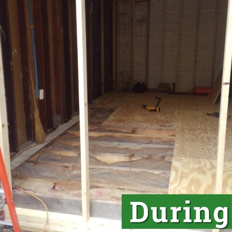 a power drill rests on plywood flooring of an unfinished converted garage