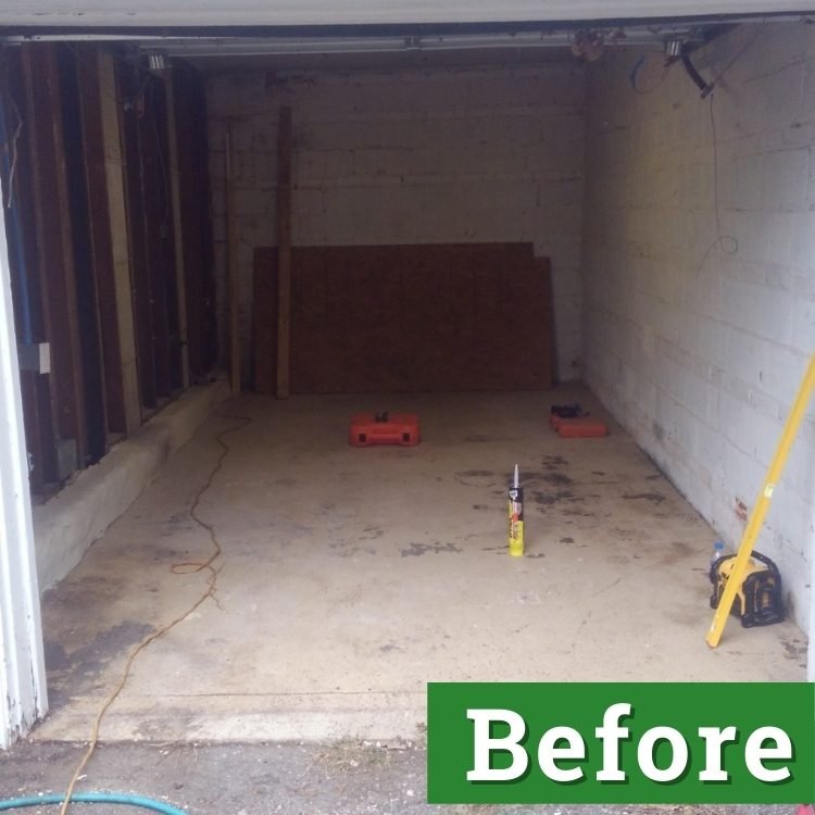 caulk and a tool box rest on the cement floor of a garage that is about to be converted into living space