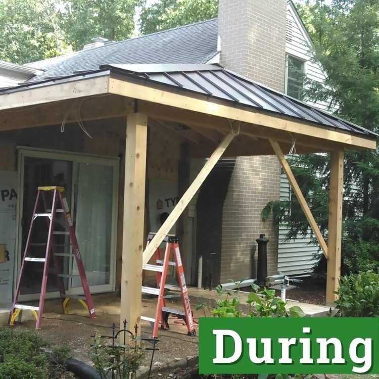 two ladders stand under new framing for an outdoor patio with partial enclosure roof